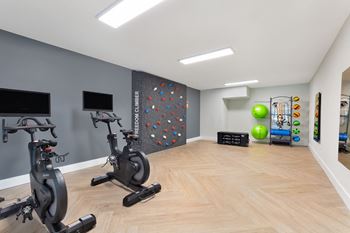 A gym with exercise machines and a rock climbing wall